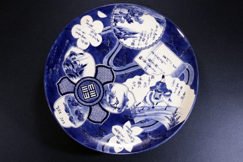 深い藍色の染付で、扇や花型の窓絵の中に異なる山水や人物、和歌が描かれた伊万里焼の大皿