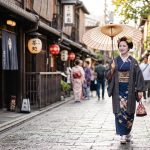 道中着を着て和傘をさし、京都の街並みを歩く着物姿の女性