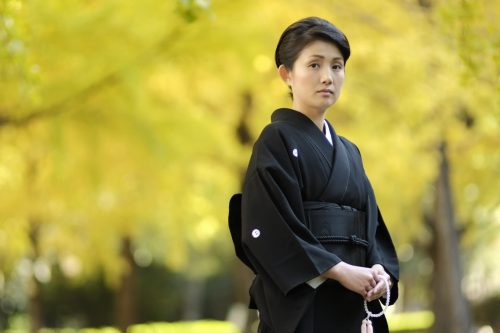 喪服着物（黒喪服）を着用し、数珠を持つ女性